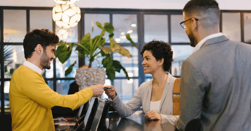 Hotel lobby receptionist returning a credit card to a customer