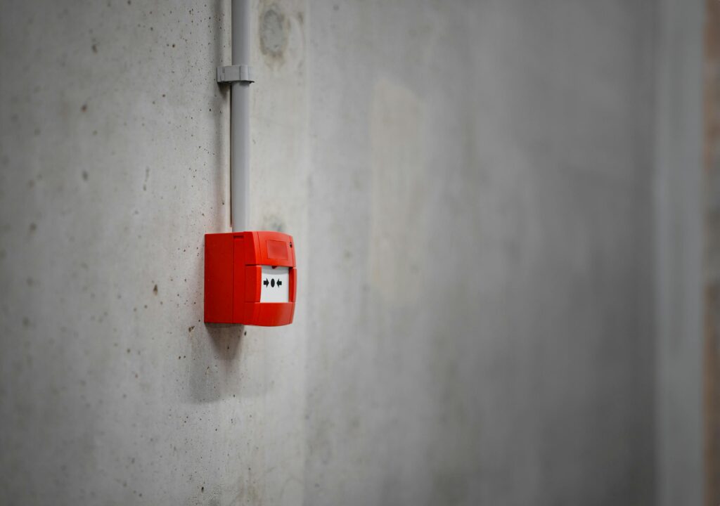 A red fire alarm box sits on a concrete wall.